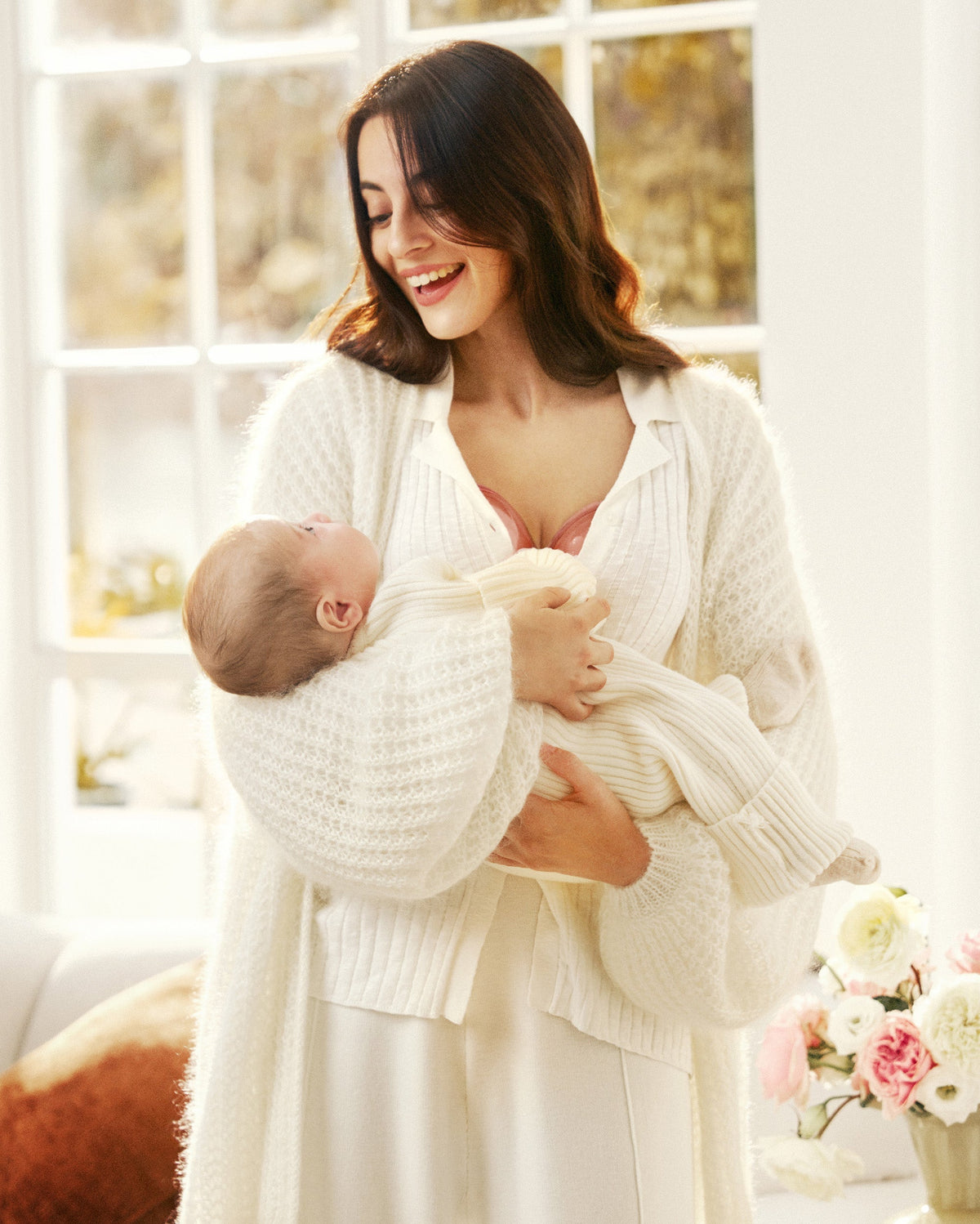 Momcozy W1 wearable breast pump worn while holding baby